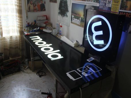 A workspace featuring a Motorola sign and a screen displaying a logo and icons.